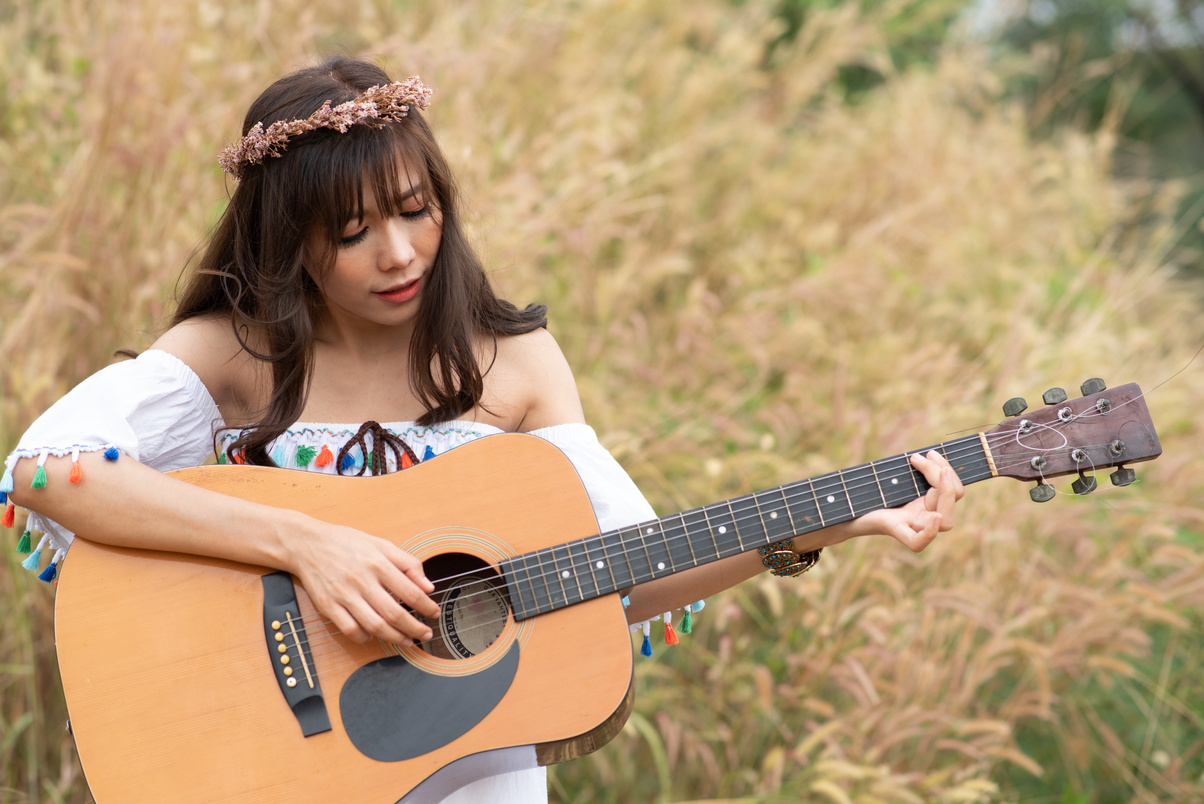 Asian Woman Playing Guitar at Beautiful Field Grass. Bohemian St
